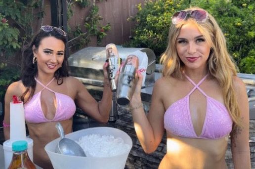 Two women in bikinis holding a bucket of ice cream.